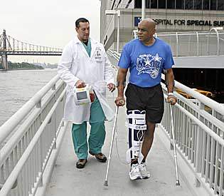Reggie Williams is assisted by physical therapist Steve Murray as he exercises by the East River while undergoing treatment for his chronic knee injury at the Hospital for Special Surgery in New York in 2008.  Associated Press file/Stuart Ramson 